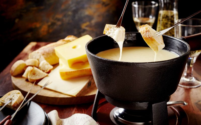 Une fondue suisse avec laquelle des personnes mettent le pain dans le fromage.