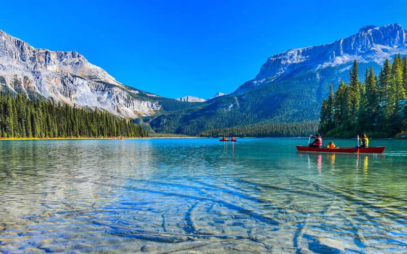 Lac canadien sous le soleil avec des expatriés faisant du kayak.